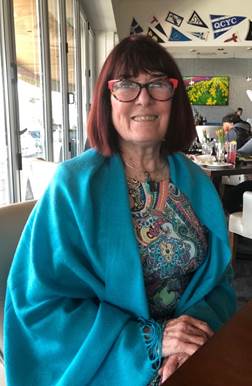 A person wearing glasses and a blue blanket  Description automatically generated